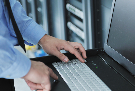 Administrator arbeitet an einer Konsole im Serverschrank